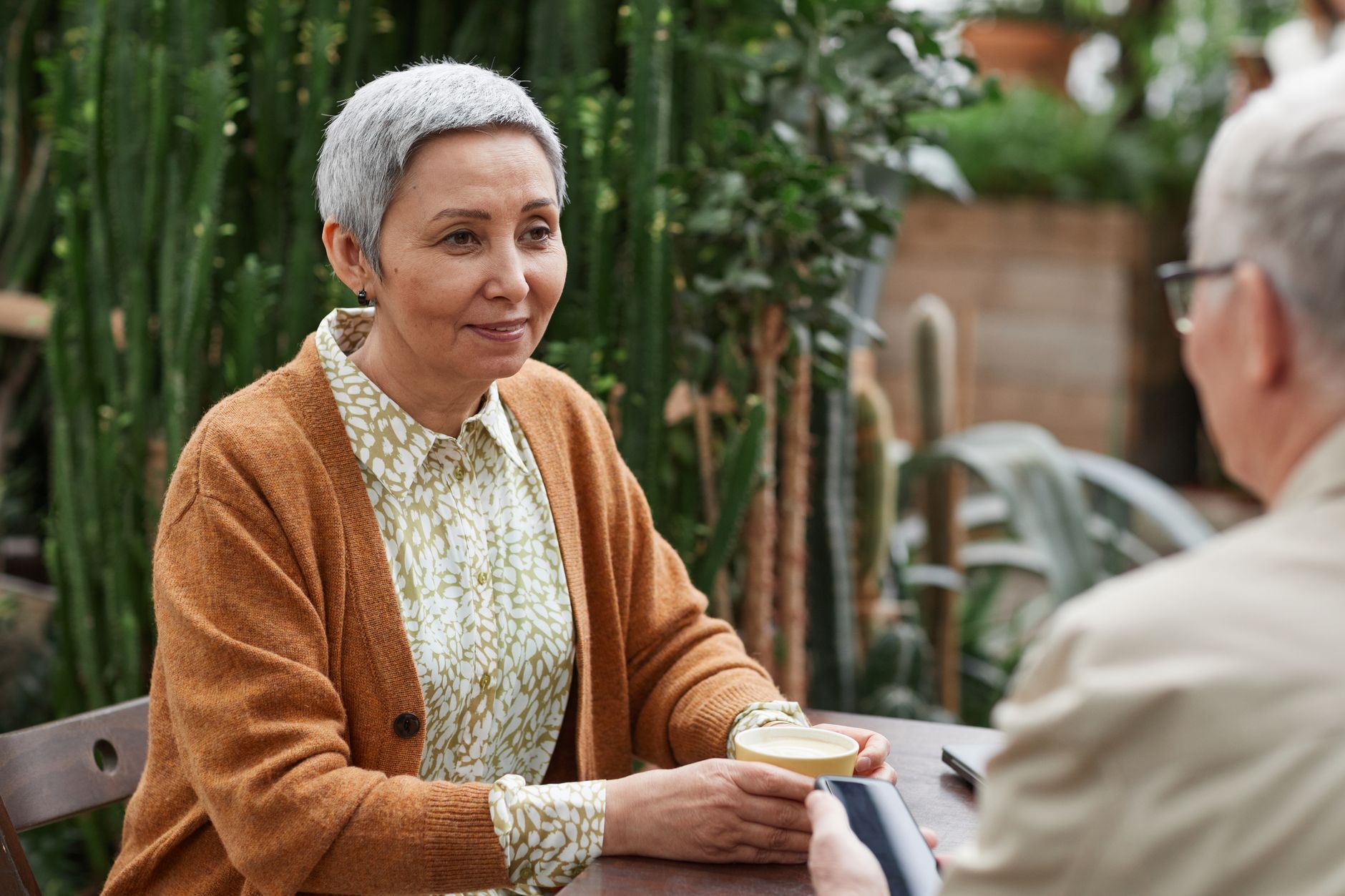 Two older adults talking at a cafe table